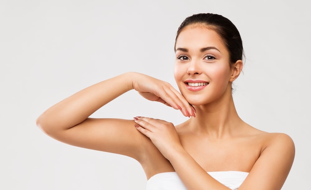 Beauty model with smooth armpit and shoulder receiving hand massage, concept of skin care, epilation, and shoulder laser hair removal.